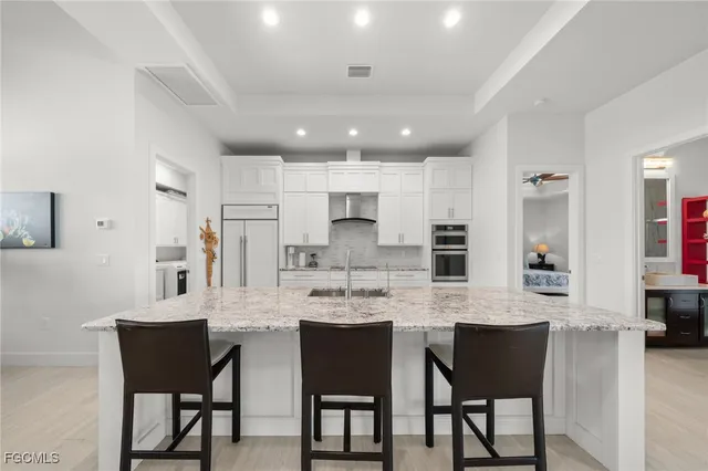a large kitchen with stainless steel appliances kitchen island granite countertop a table chairs and a refrigerator