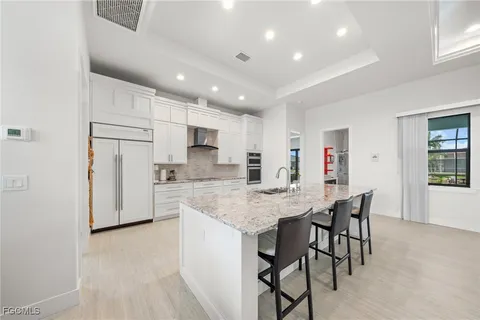 a kitchen with stainless steel appliances granite countertop a table chairs sink refrigerator and cabinets