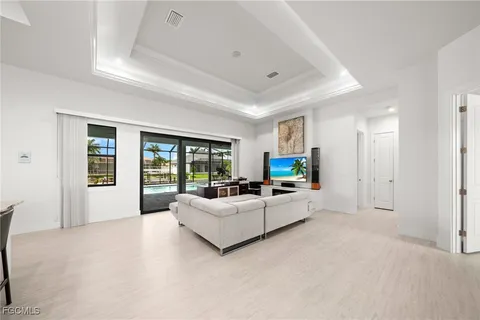 a large white bed in a white room with couch and a large window