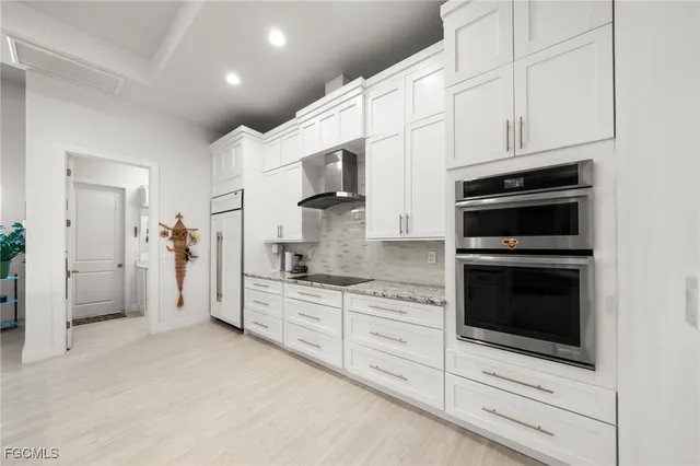 a kitchen with granite countertop white cabinets and stainless steel appliances