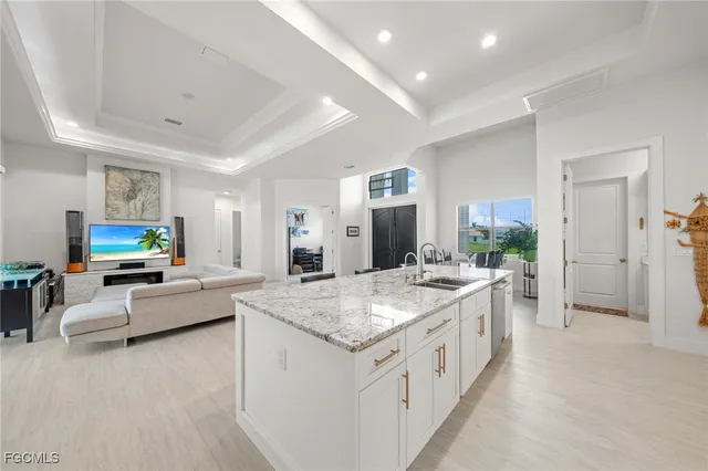a large white kitchen with a stove a sink a couch and a flat screen tv