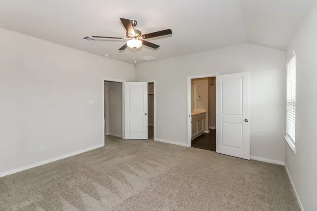 a view of an empty room and chandelier fan