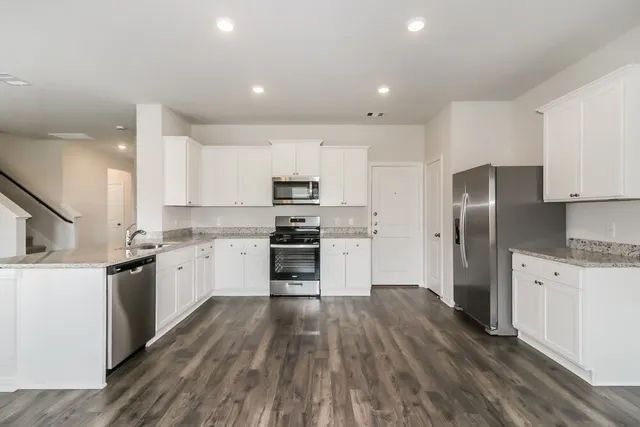 a kitchen with cabinets wooden floor and stainless steel appliances