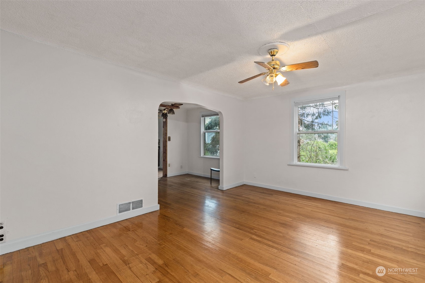 666 Sunset Boulevard Northeast Renton, WA 98056 - Photo 4 of 39 an empty room with wooden floor chandelier fan and windows
