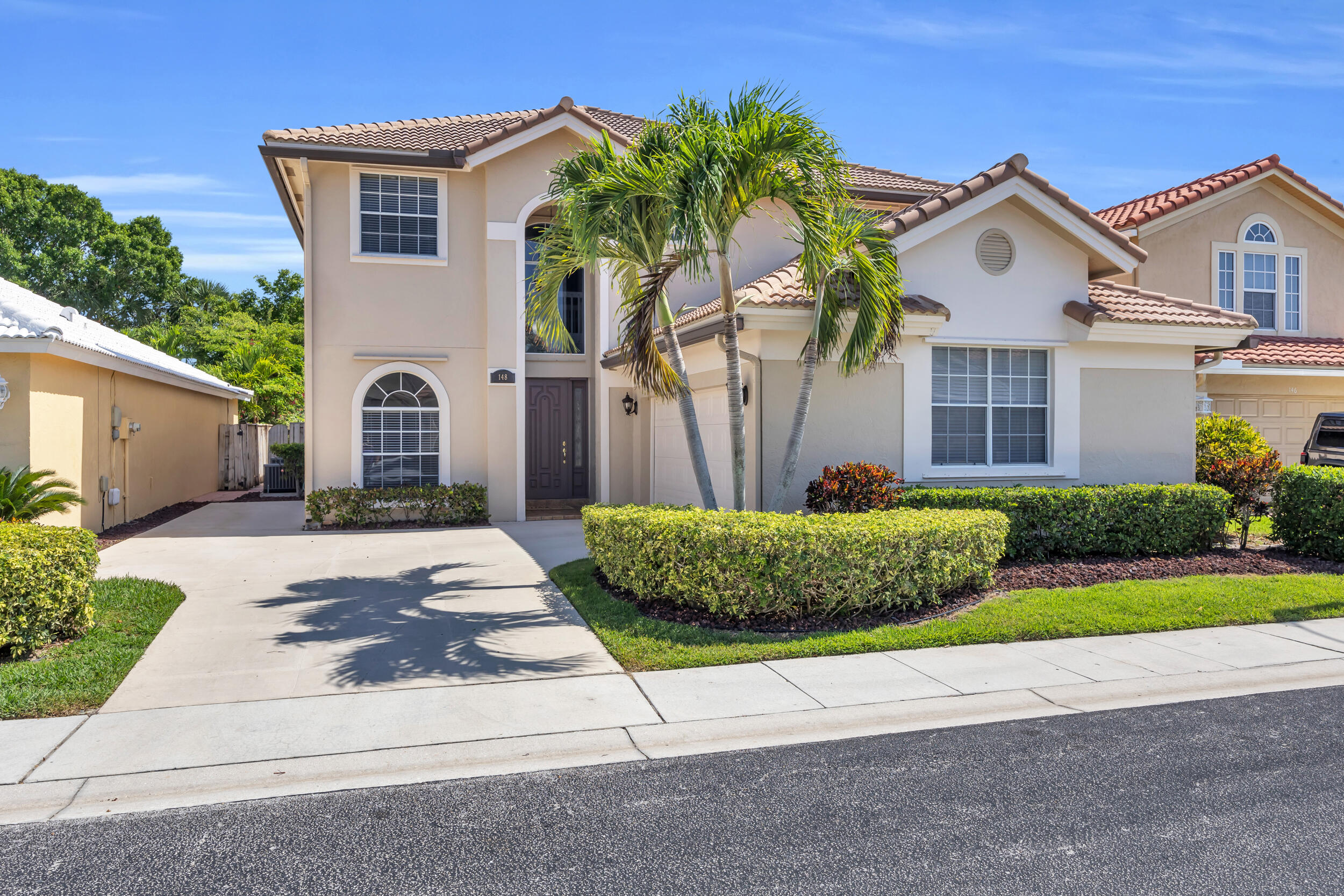 148 Cypress Cove Jupiter, FL 33458 - Photo 2 of 53 a front view of a house with a garden and plants