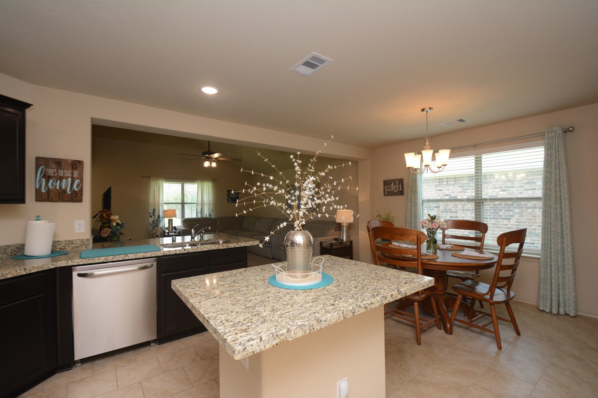 23318 Dukes Run Drive Spring, TX 77373 - Photo 2 of 41 This photo showcases an open-concept kitchen and dining area with granite countertops, dark cabinetry, and a cozy dining nook. The space is brightened by large windows and a modern chandelier, providing a welcoming atmosphere.