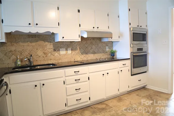 a kitchen with granite countertop white cabinets and white appliances