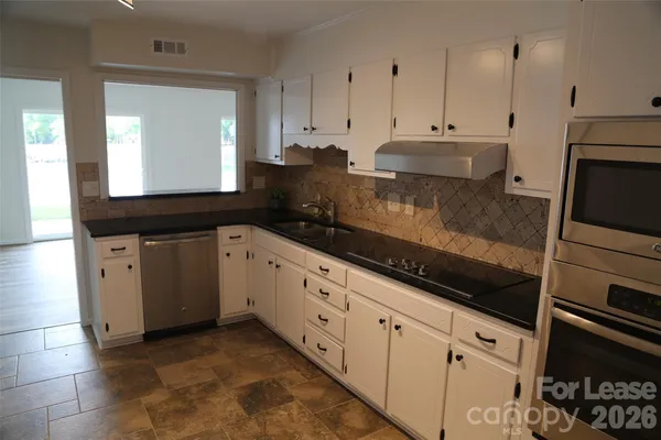 a kitchen with granite countertop white cabinets and black appliances