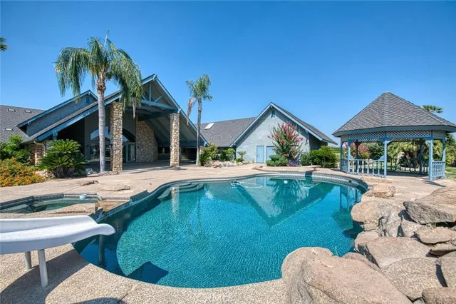 a view of swimming pool with lawn chairs and plants
