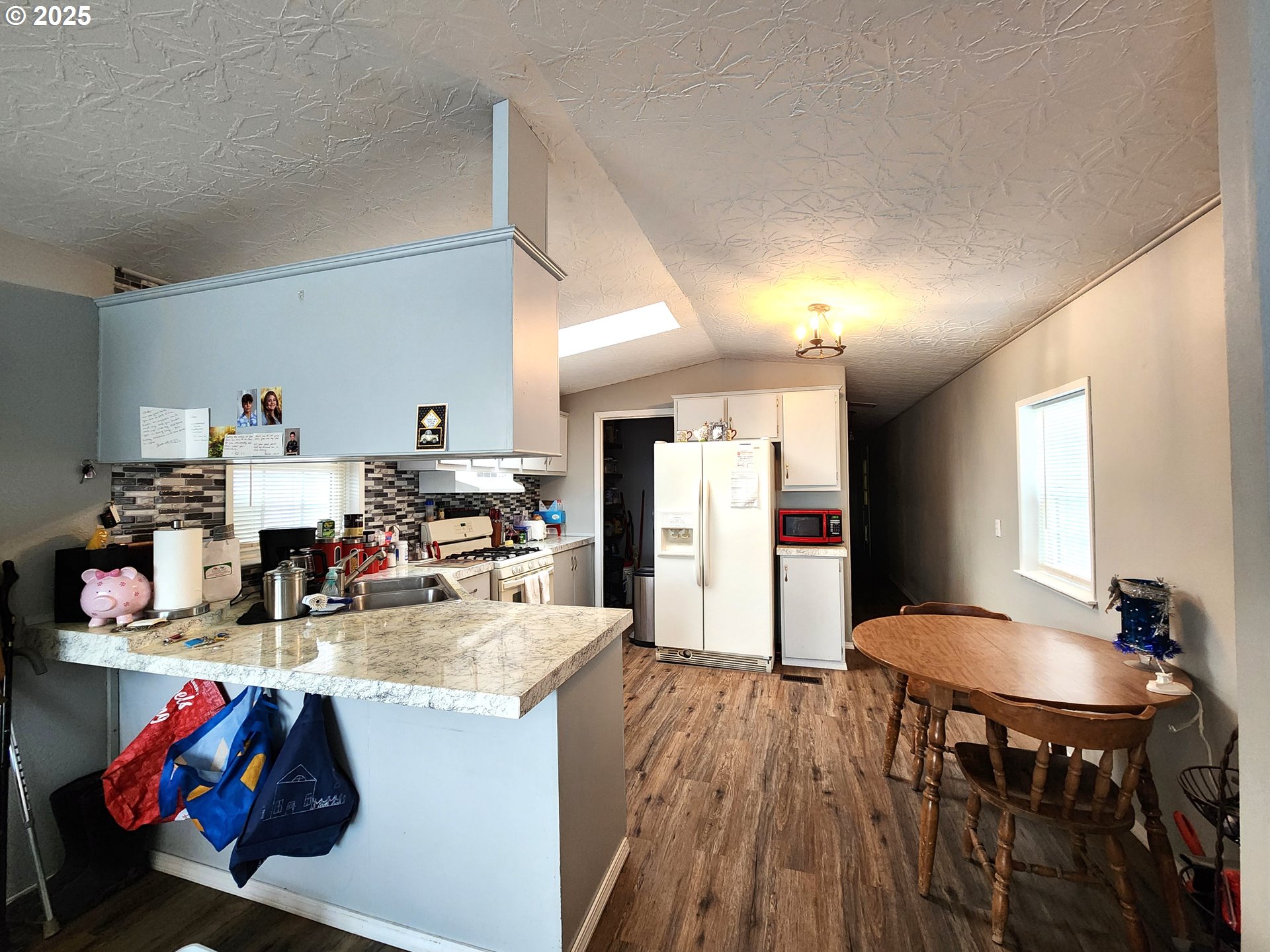 1601 Carolyn Terrace, Unit 9 Elgin, OR 97827 - Photo 4 of 7 a kitchen with stainless steel appliances kitchen island granite countertop a table chairs in it and wooden floors