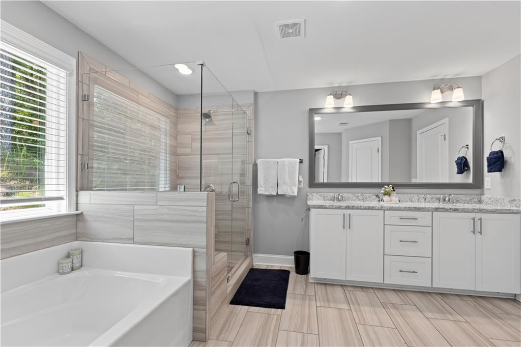 540 Glen Abbey Circle Mableton, GA 30126 - Photo 31 of 47 a bathroom with a granite countertop sink a large mirror and a bathtub