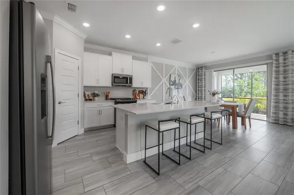 a kitchen with microwave a refrigerator and chairs