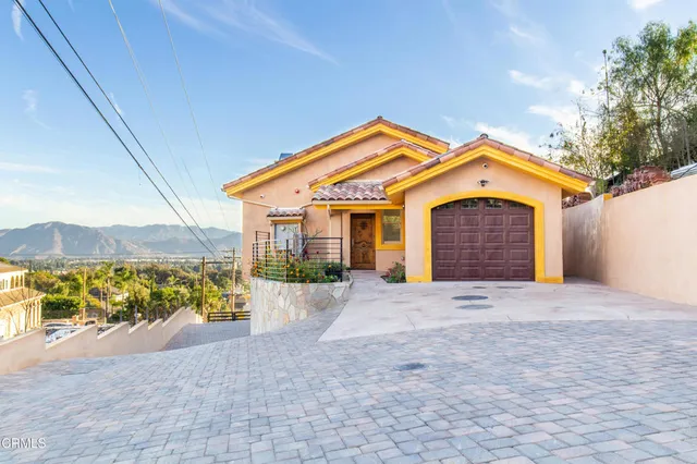 a front view of a house with a yard and mountain view