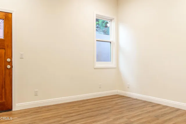 a view of an empty room with wooden floor and a window