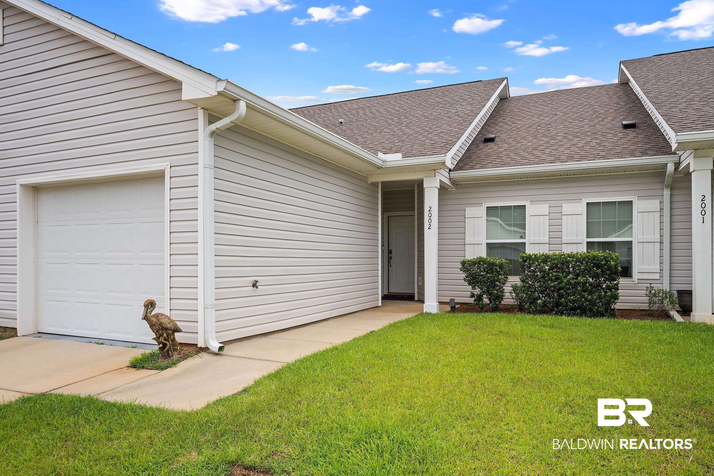 2651 South Juniper Street, Unit 2002 Foley, AL 36535 - Photo 1 of 23 Townhome exterior featuring light-colored siding, a brown shingled roof, an attached garage, and a concrete driveway