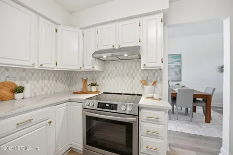 a kitchen with a stove and white cabinets