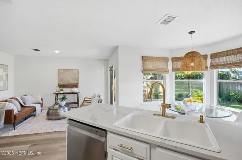 a kitchen with a sink a counter top space and living room view