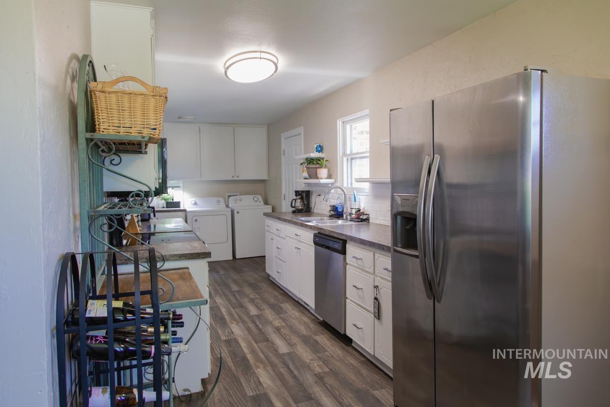 1404 Rochester Street Caldwell, ID 83605 - Photo 6 of 29 Kitchen featuring stainless steel appliances, wood-finish flooring, white cabinetry, and a utility area with a washer and dryer