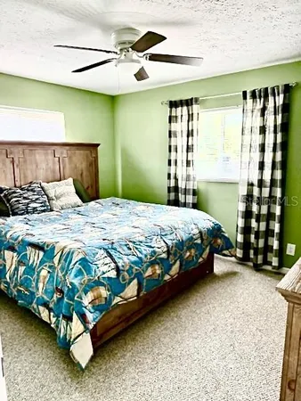 a bedroom with a bed painting and a large window