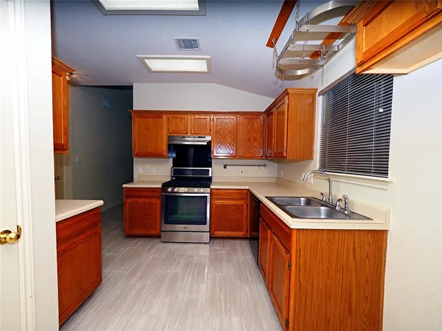 a kitchen with stainless steel appliances granite countertop a sink stove and wooden cabinets