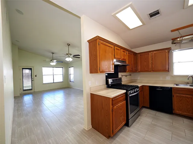 a kitchen with stainless steel appliances granite countertop wooden cabinets a stove a sink and a window
