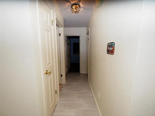 a view of a hallway with wooden floor and a white wall