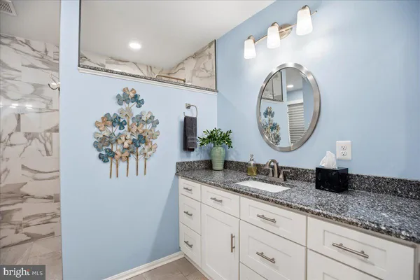 a bathroom with a granite countertop double vanity sink and a mirror