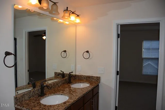 a bathroom with a granite countertop sink a mirror and shower