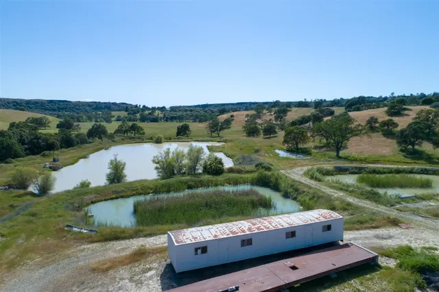 an aerial view of ocean with residential houses with outdoor space and trees all around