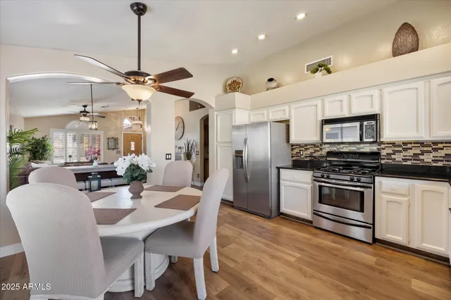 a kitchen with stainless steel appliances a dining table chairs stove and refrigerator