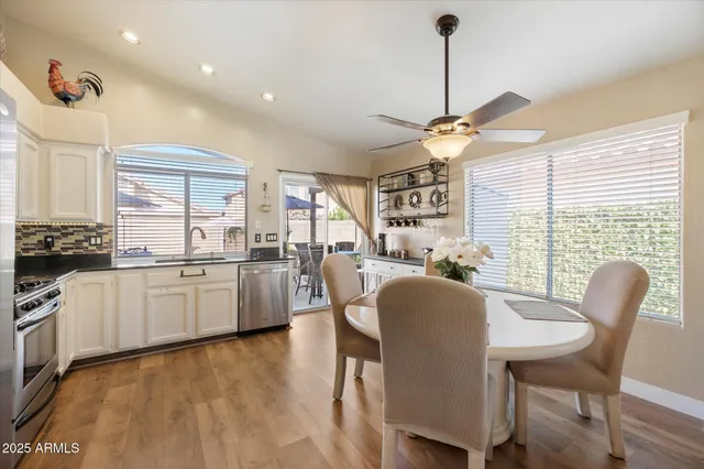 a kitchen with stainless steel appliances granite countertop a stove a sink dishwasher a dining table and chairs with wooden floor