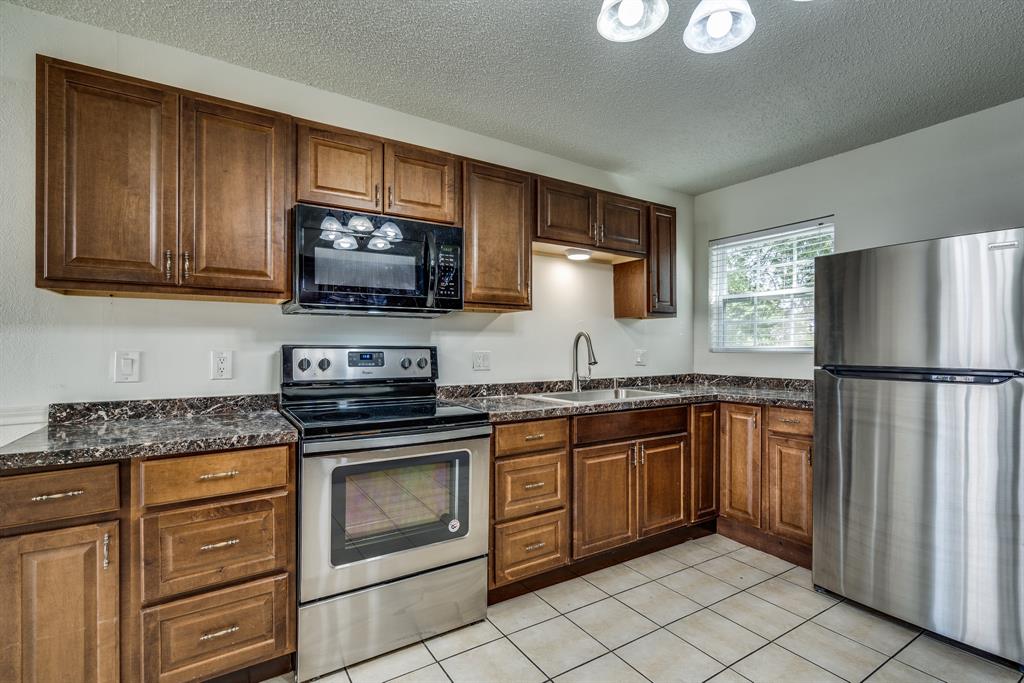 116 North 12th Street, Unit B Midlothian, TX 76065 - Photo 16 of 24 a kitchen with granite countertop stainless steel appliances and wooden cabinets