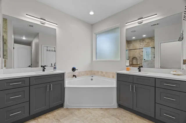 a bathroom with a tub a double vanity sink and mirror