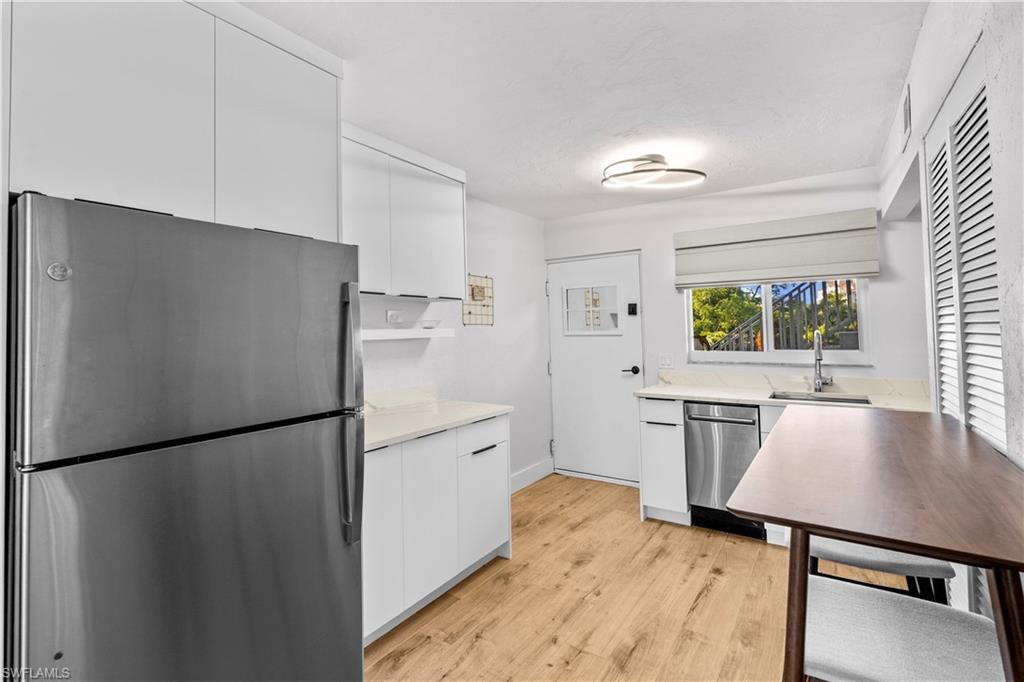 377 Vanderbilt Beach Road, Unit 102 Naples, FL 34108 - Photo 6 of 19 a kitchen with stainless steel appliances a refrigerator a sink a stove a dining table and chairs