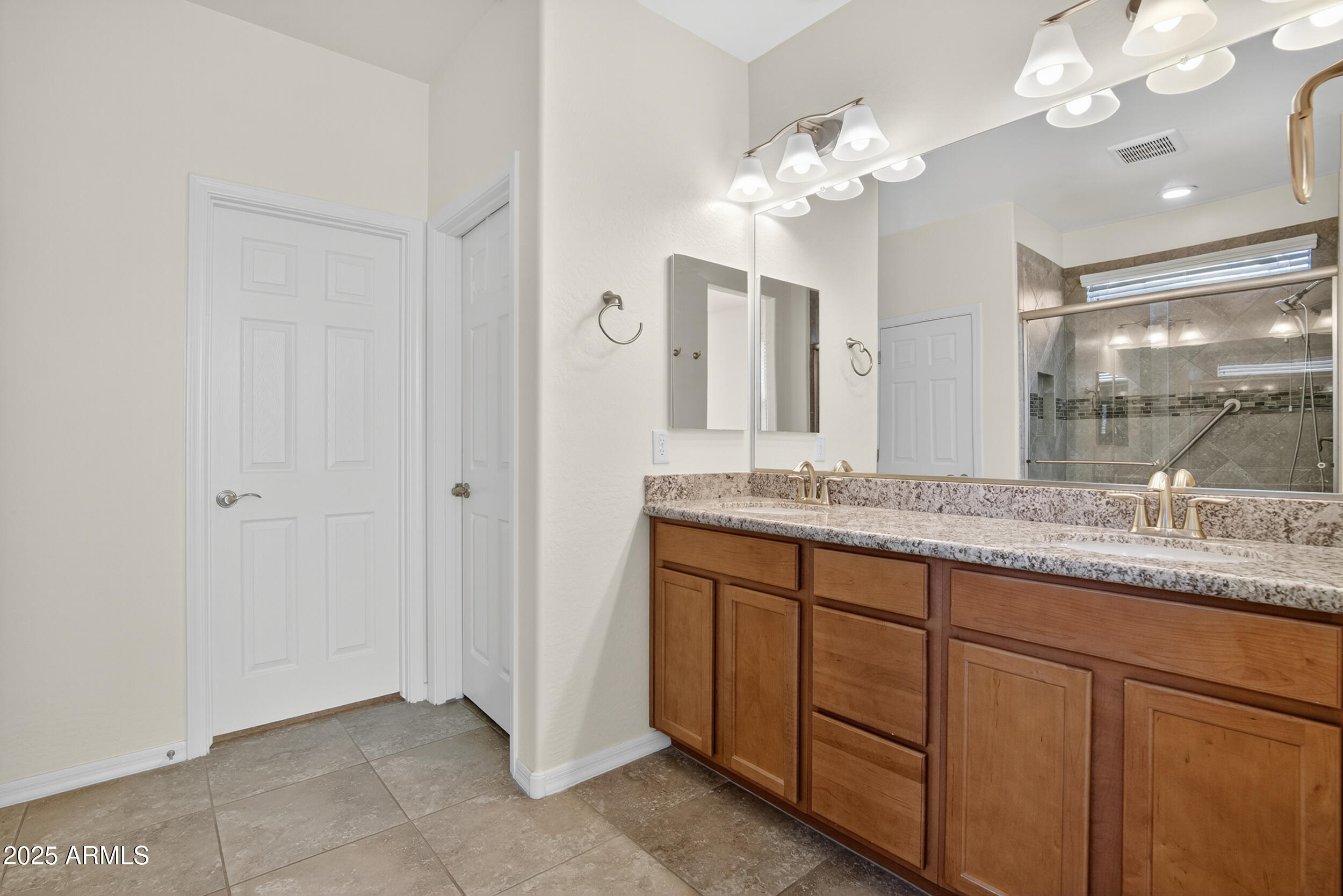 17763 West Granite View Drive Goodyear, AZ 85338 - Photo 22 of 67 a bathroom with a granite countertop sink a large mirror and a shower