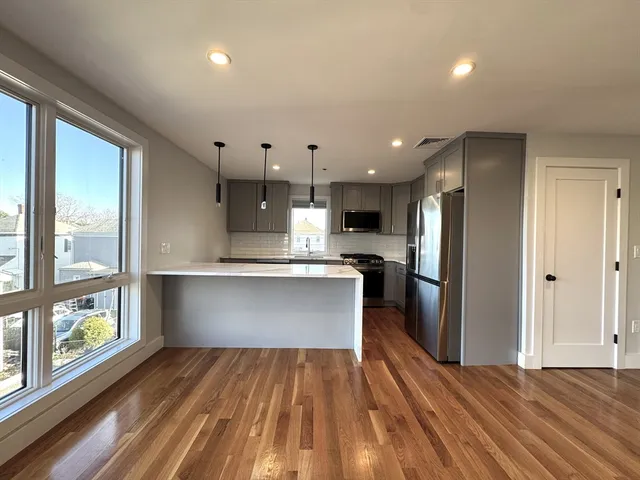a view of kitchen with stainless steel appliances kitchen island wooden floor and window