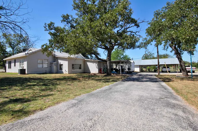 a view of a house with a yard and large tree
