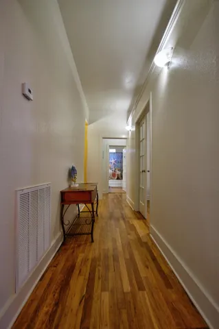 a view of a hallway with wooden floor and furniture