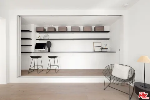 a living room with a chair and white cabinet with wooden floor