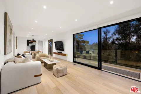 a living room with furniture a flat screen tv and a floor to ceiling window