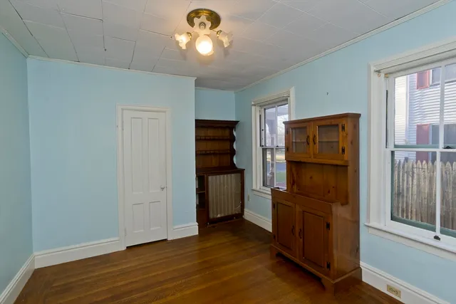 an empty room with wooden floor cabinet and windows