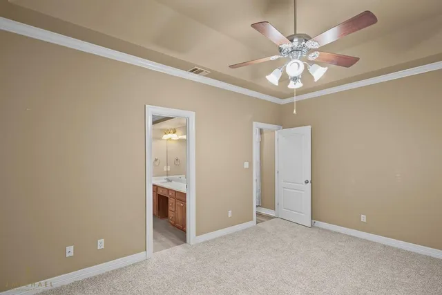an empty room with chandelier fan and windows
