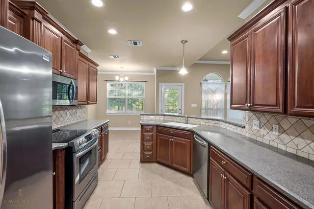a large kitchen with stainless steel appliances granite countertop a sink and a stove