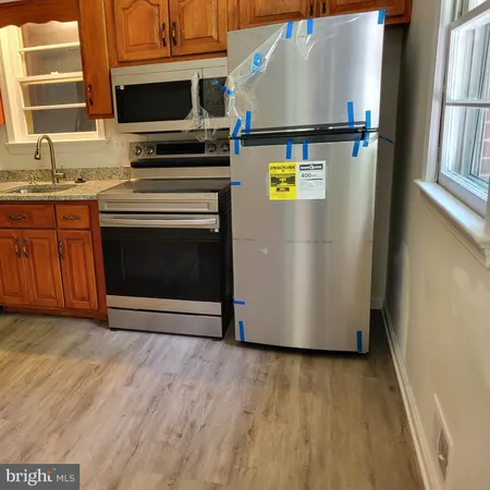 a view of a kitchen with wooden floor electronic appliances and windows