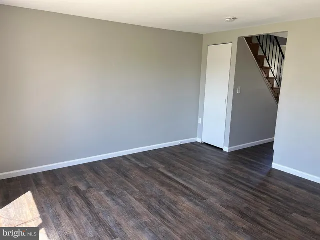 a view of an empty room with wooden floor and closet