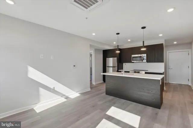 a view of kitchen with stainless steel appliances kitchen island wooden floor and living room view