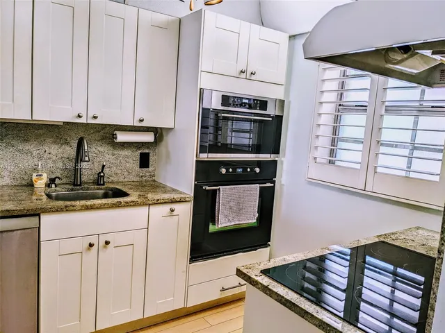 a kitchen with granite countertop a stove sink and cabinets