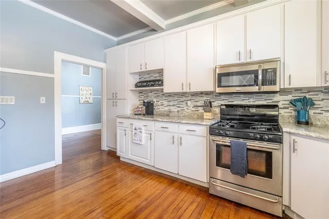 a kitchen with stainless steel appliances white cabinets a stove a sink and a microwave