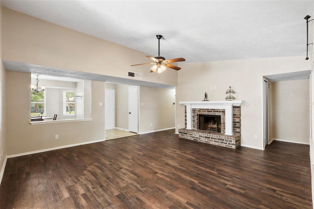 9212 Shipman Street Rowlett, TX 75088 - Photo 12 of 34 Unfurnished living room featuring dark wood finished floors, a brick fireplace, and a ceiling fan