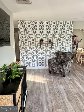 a living room with a couch wooden floor and a potted plant